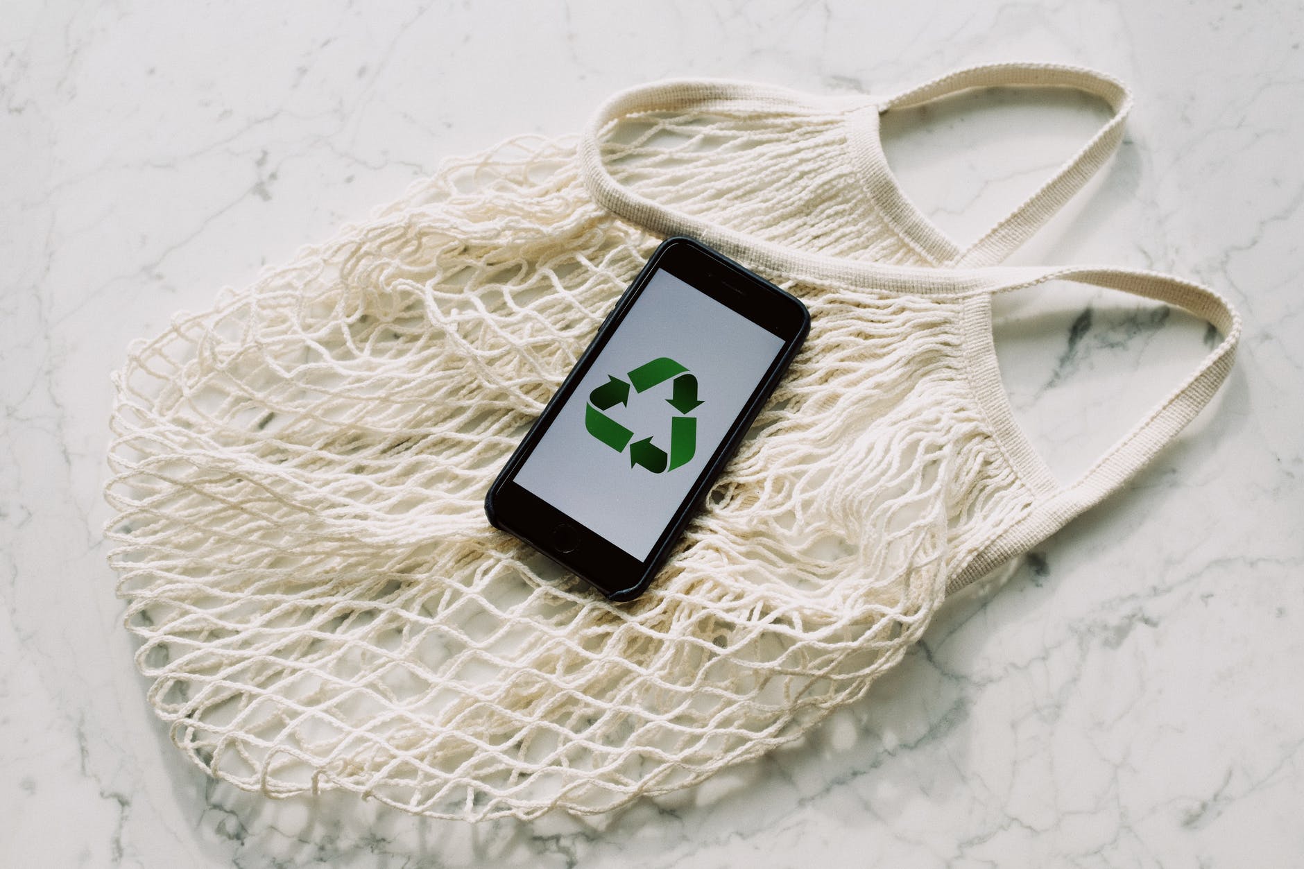 mesh bag with a recycling logo on a phone suggesting environmental sustainability